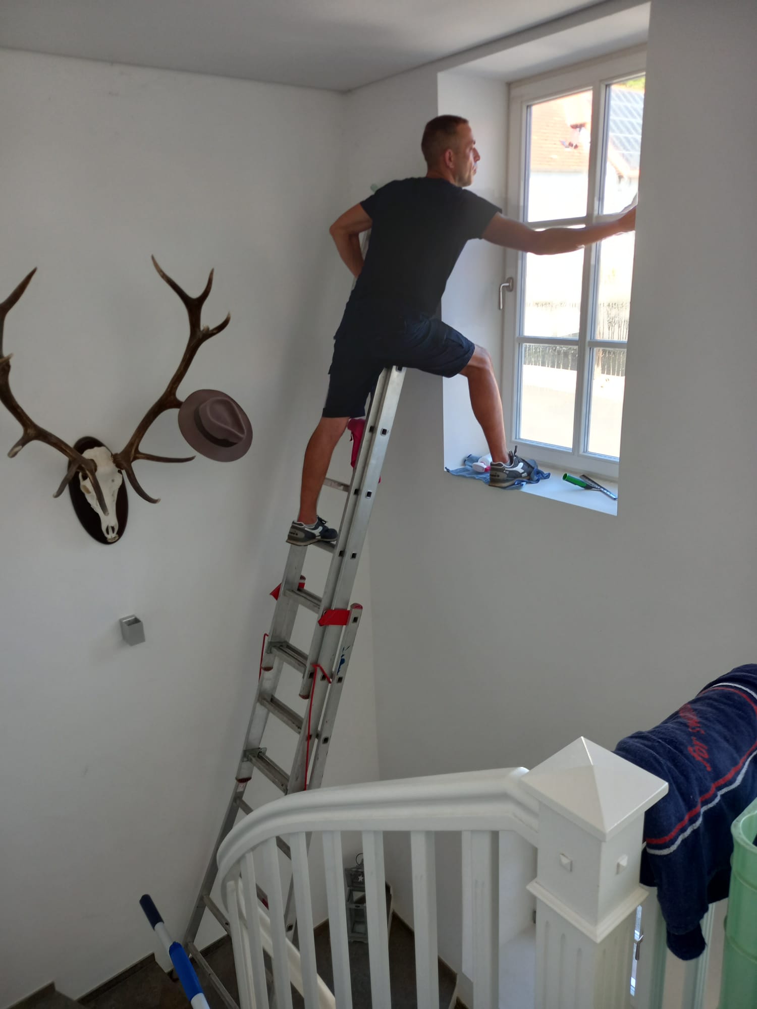 Mitarbeiter bei der Fensterreinigung von der Leiter aus